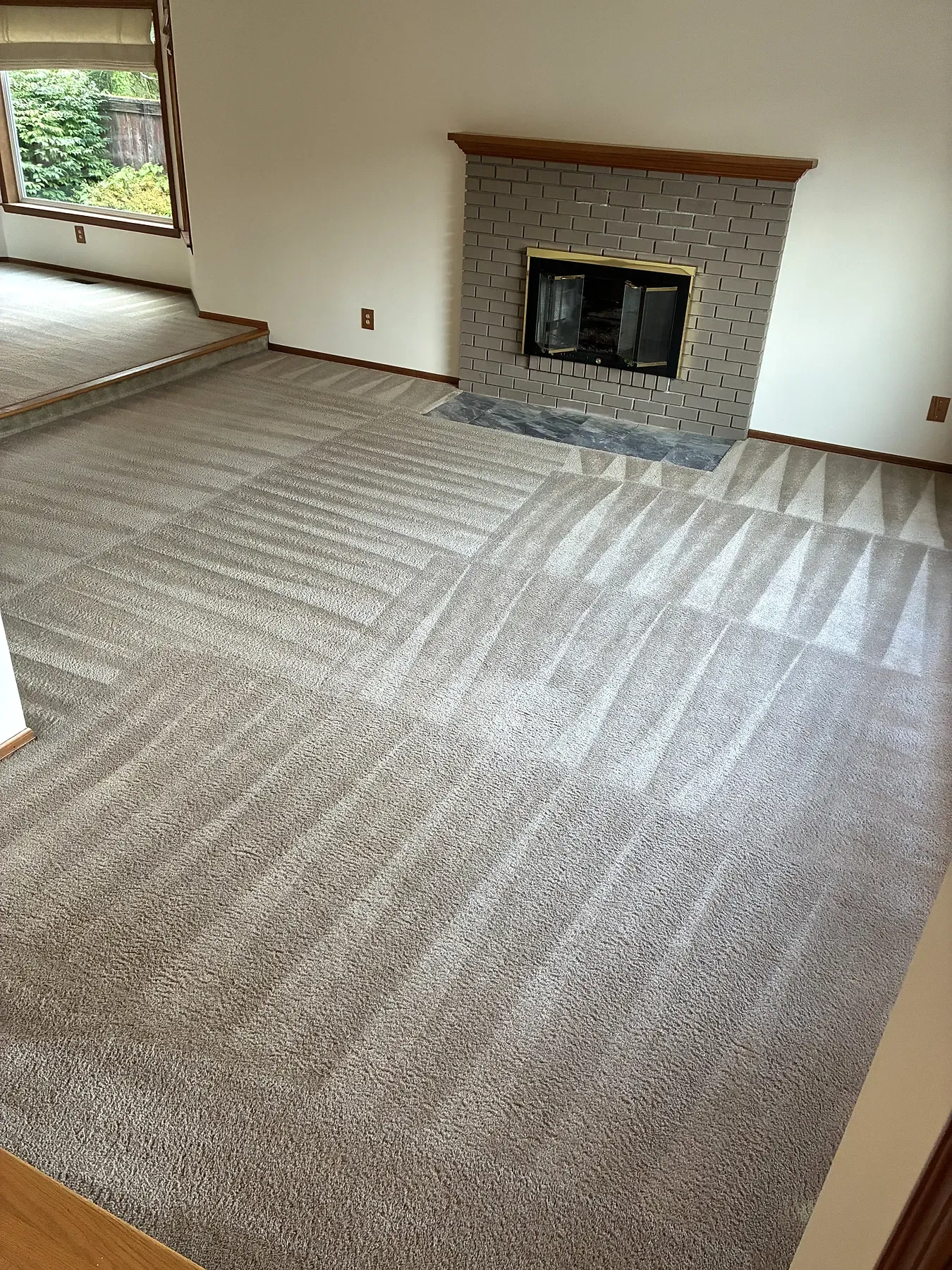 Freshly cleaned living room carpet in front of a brick fireplace